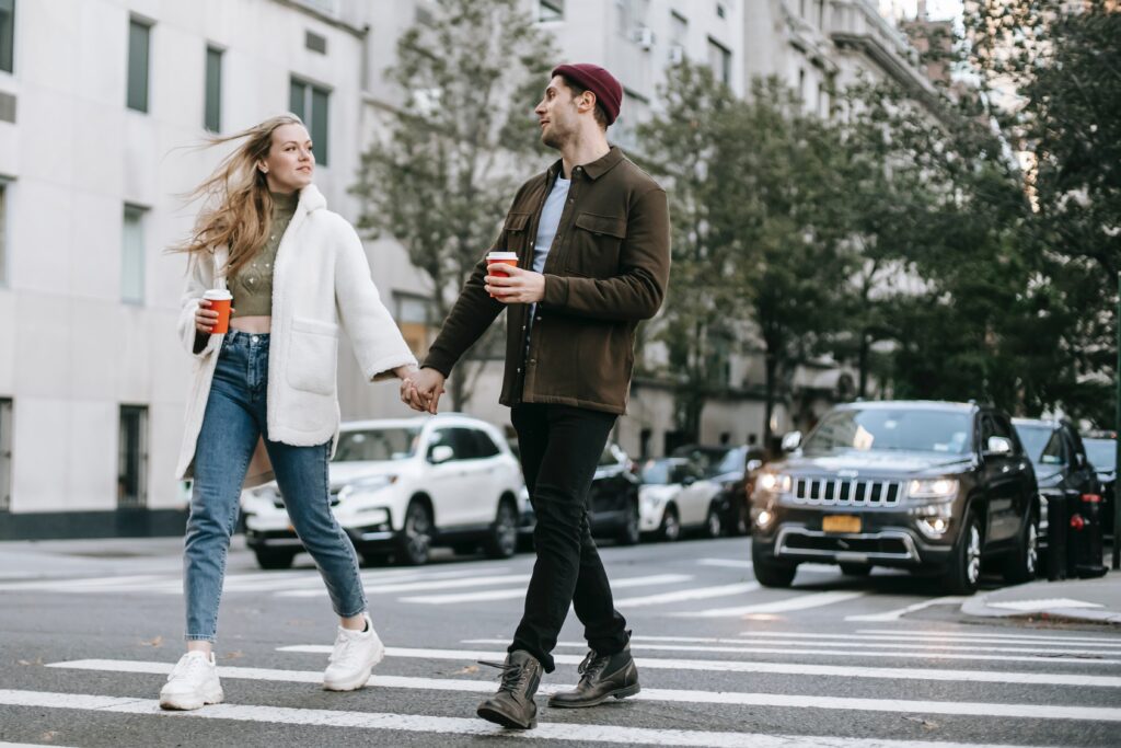 man and woman walking through crosswalk holding hands