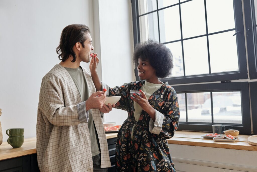 Woman Feeding Strawberries to a Man and Smiling