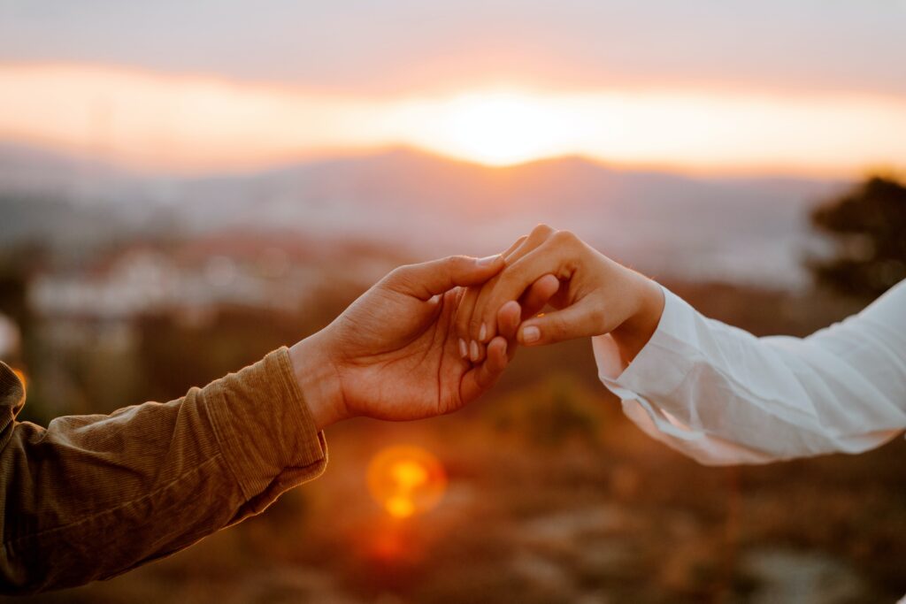 polyamorous couple holding hands at sunset