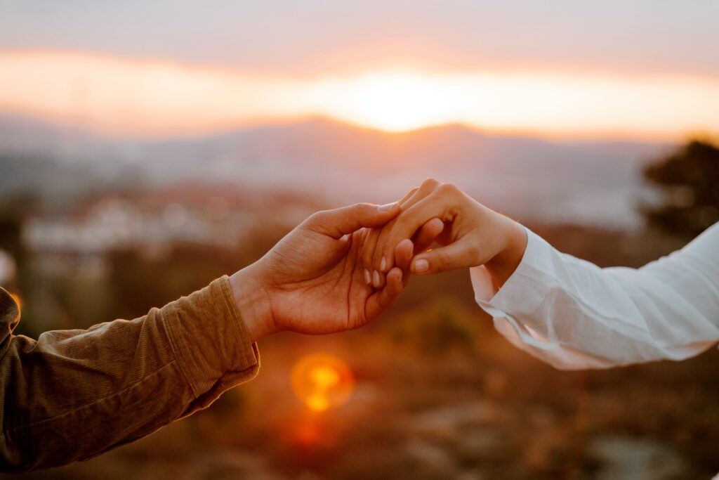 swinger couple holding hands at sunset