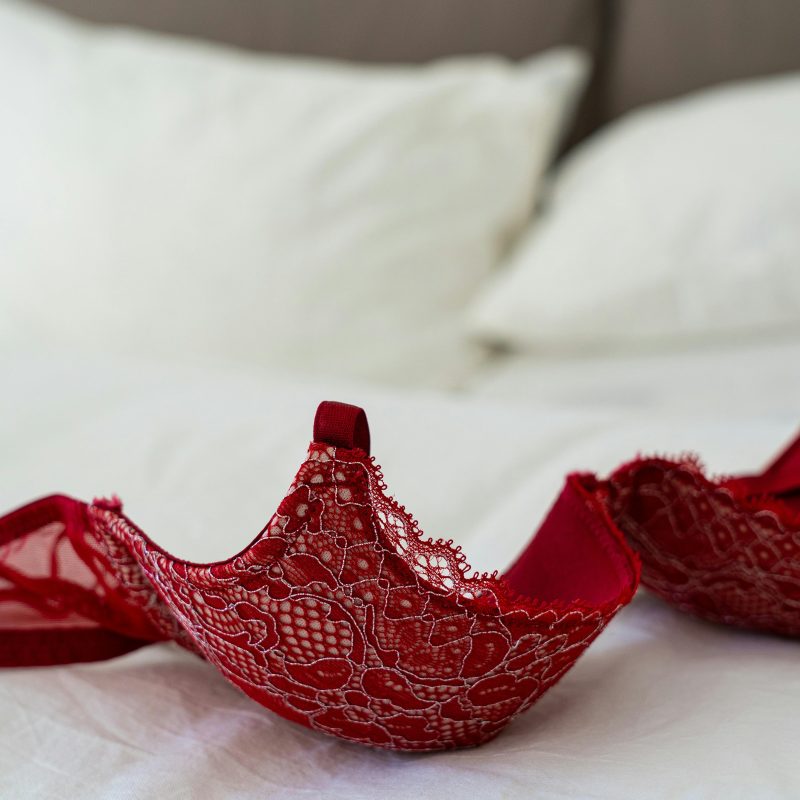 Red Lace Brassiere on White Bed at a Group Sex Party
