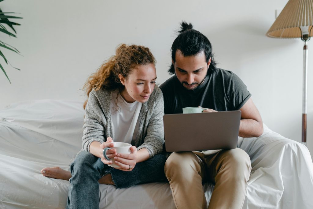 Happy couple using laptop while browsing swinger dating sites