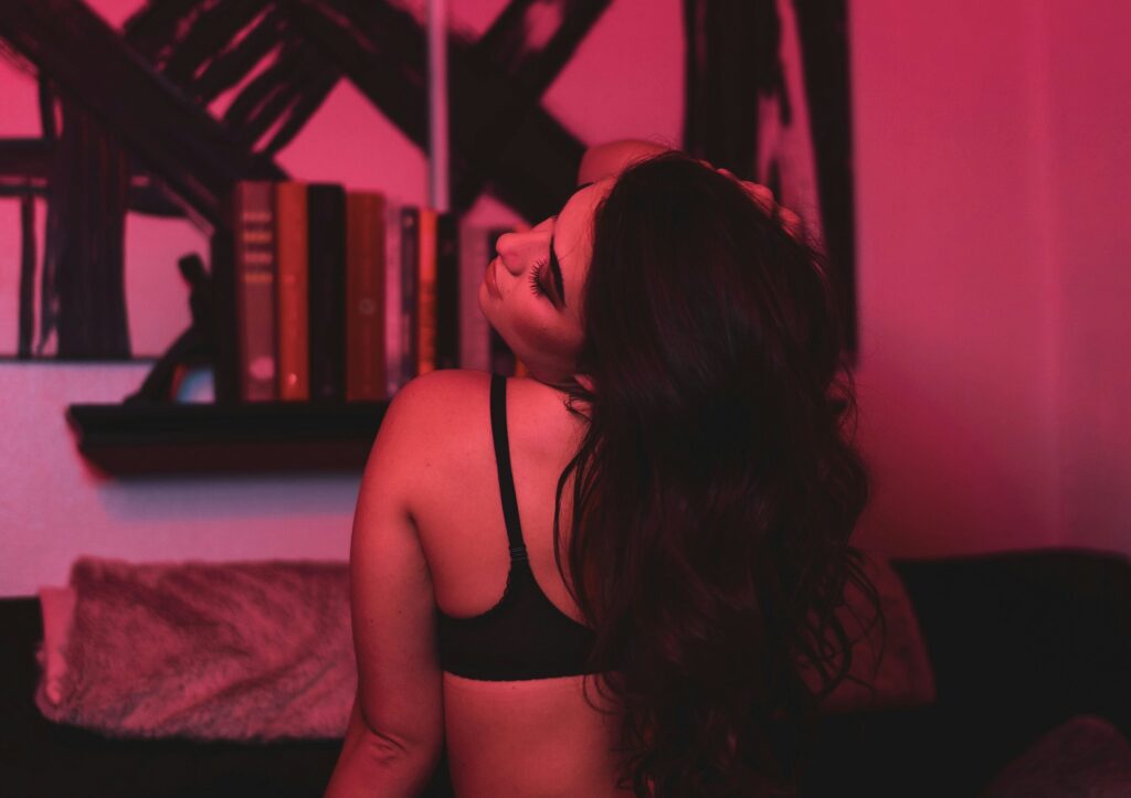 The image features an individual in a room lit with red lighting, with shelves and a cozy looking corner visible in the background.