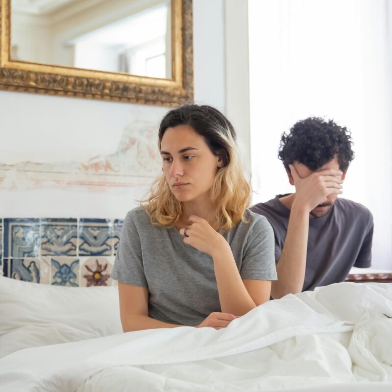 Woman in Gray Shirt Sitting Beside Man in Bed