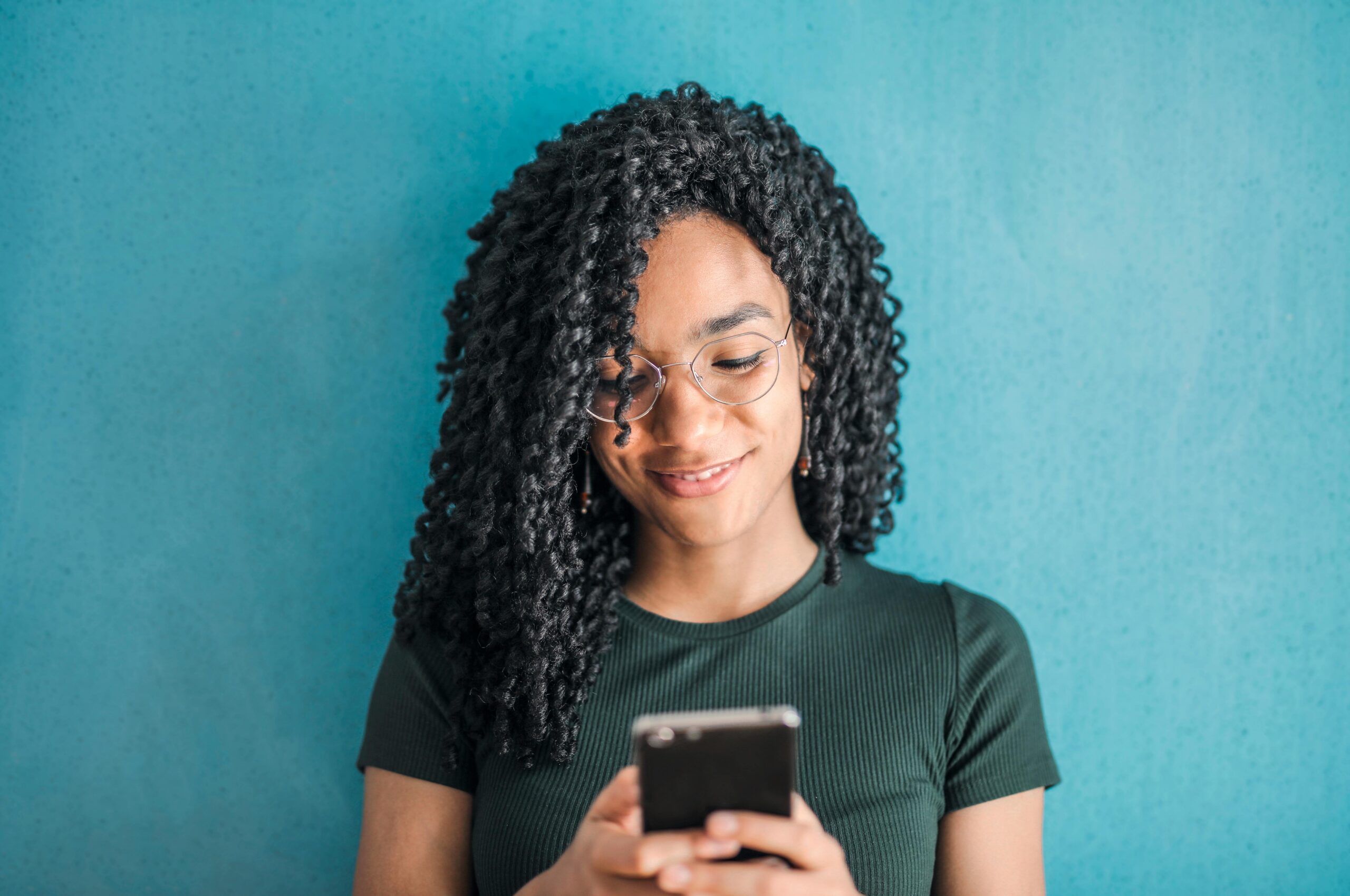 Portrait Photo of Smiling Woman in Black T-shirt Looking at Sext Message