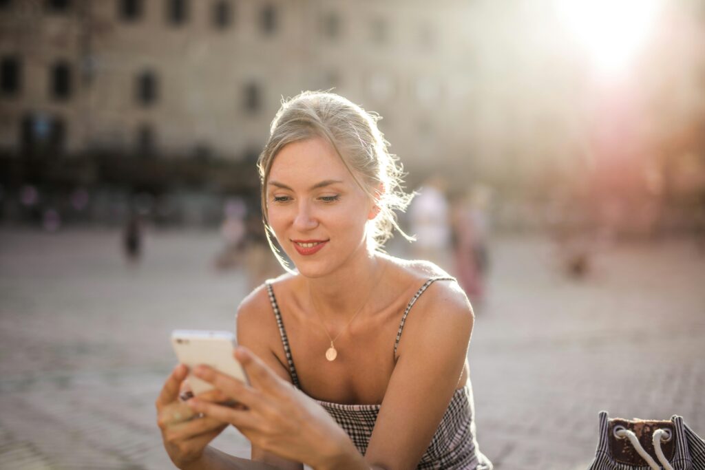 Woman in White and Black Stripe Spaghetti Strap Top Holding Phone