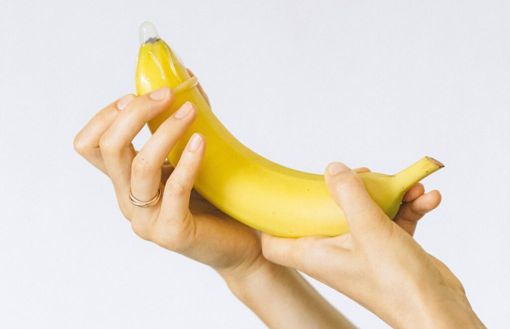 Person Wrapping Condom on Banana
