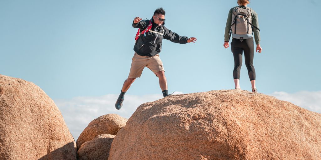 men jumping between big rocks