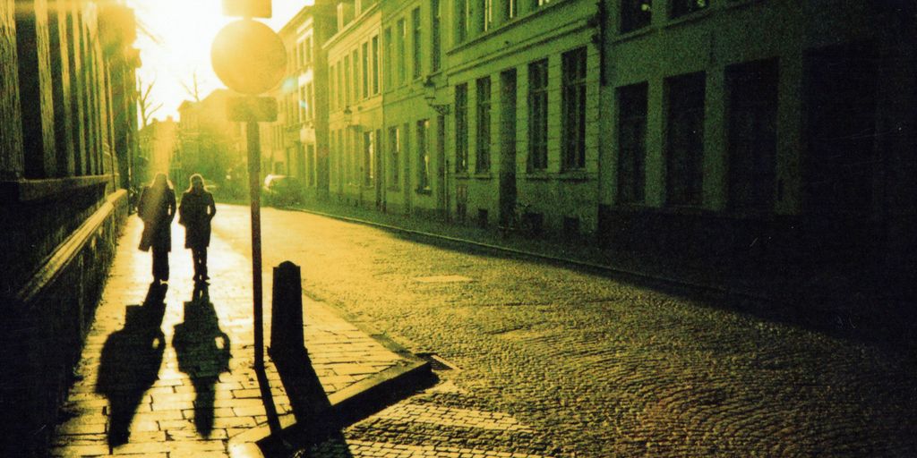 man in black jacket and pants walking on sidewalk during night time