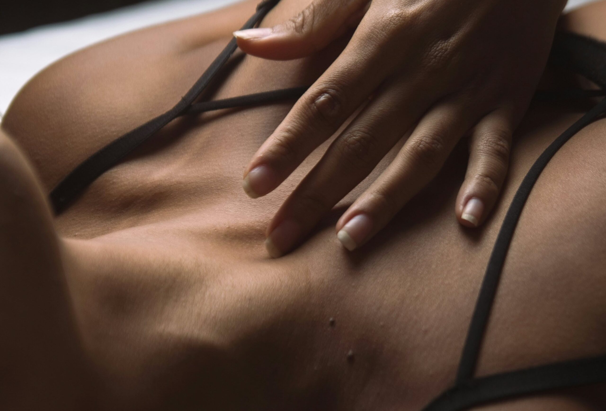a woman laying on top of a bed wearing a black bra
