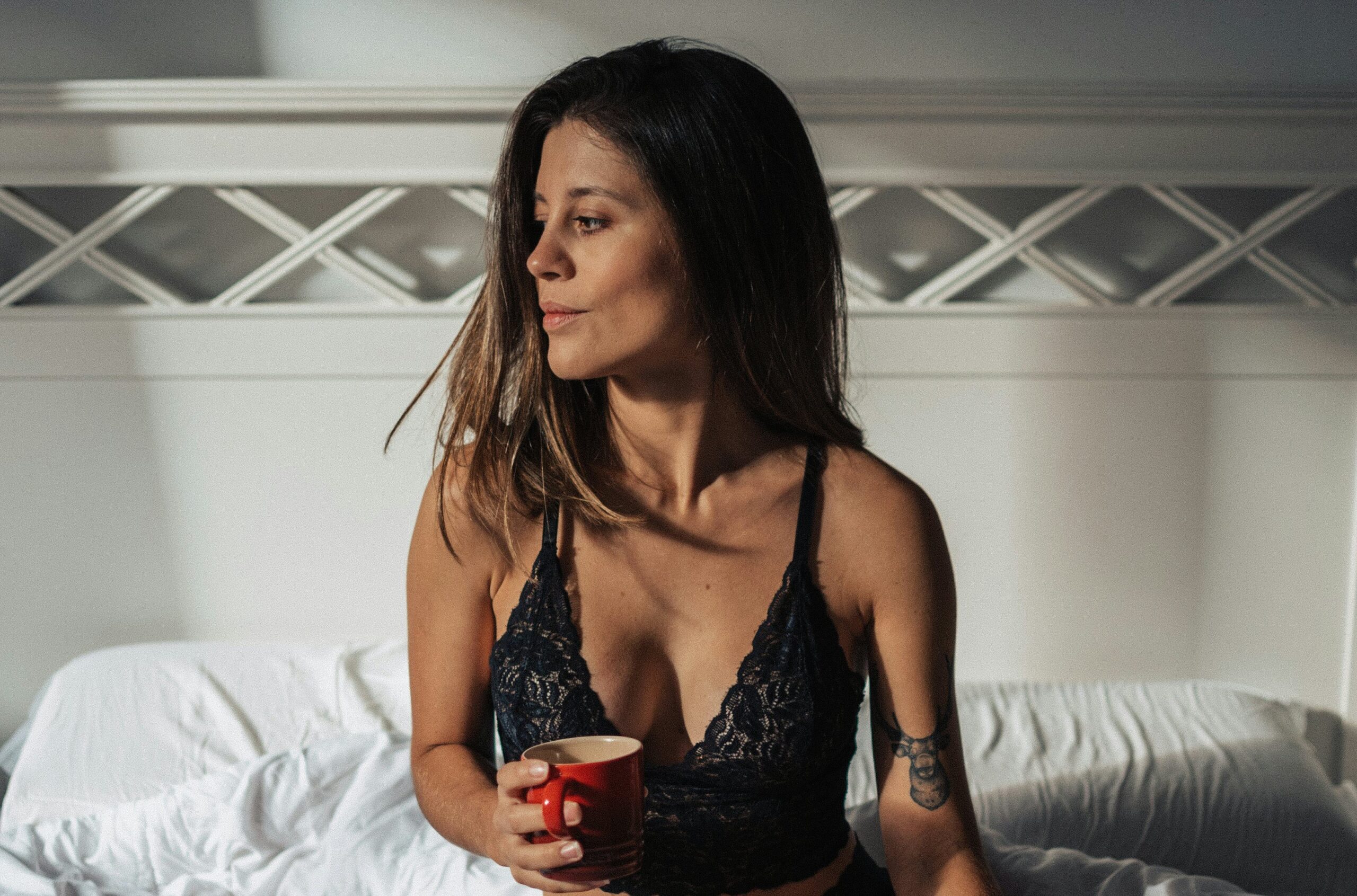 woman wearing black bra and panties sitting on bed