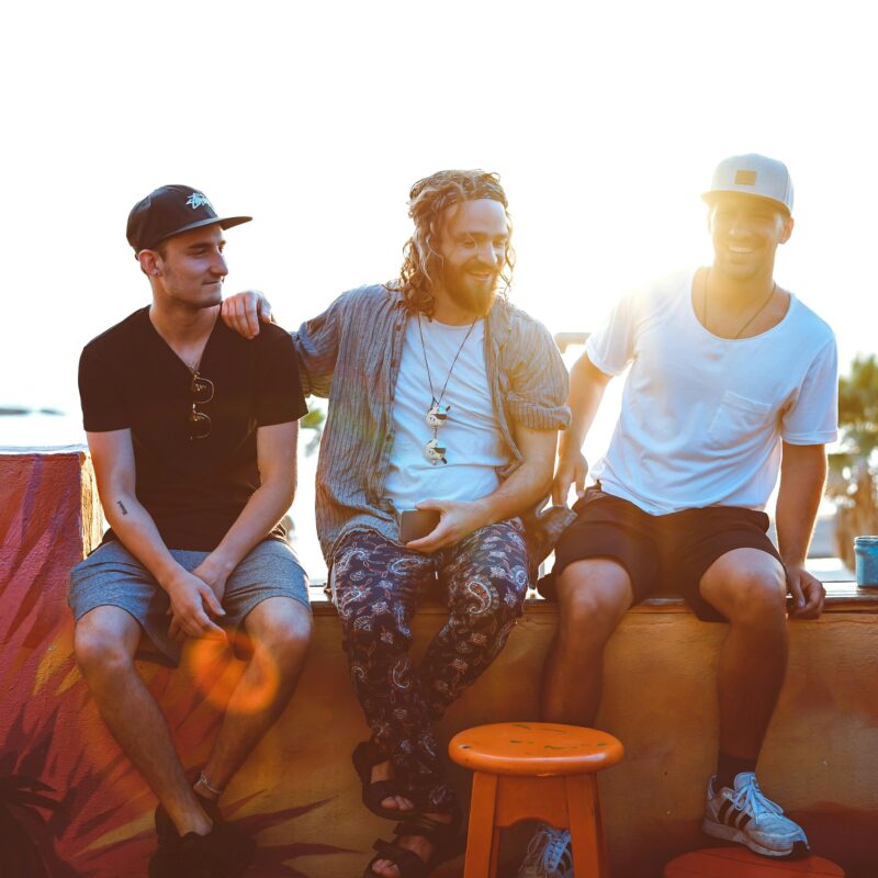 three men sitting on gray surface