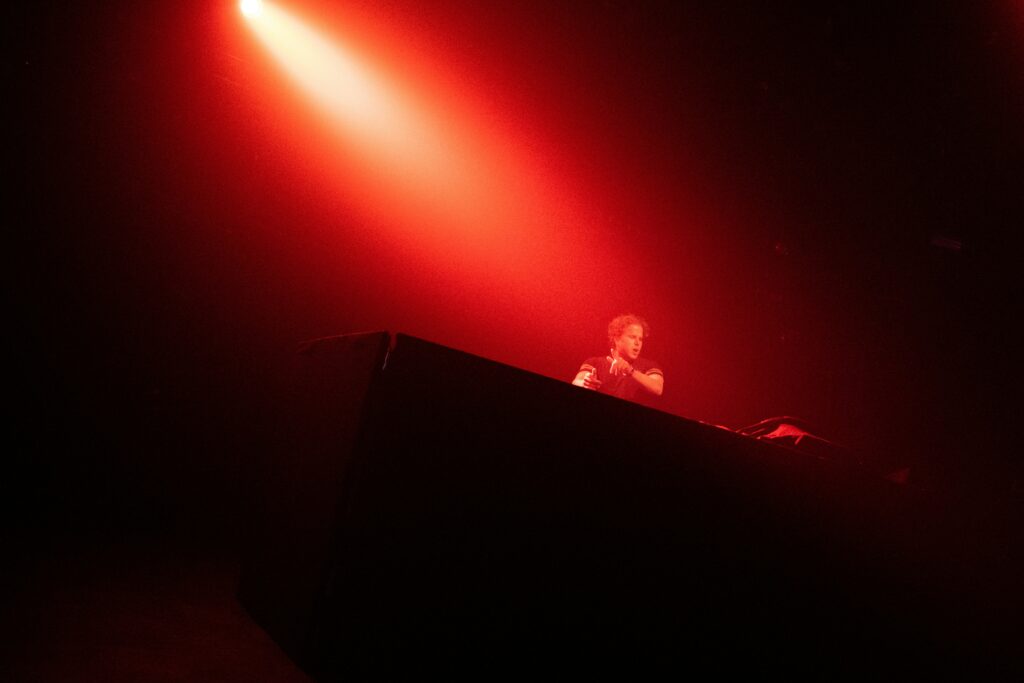 A man playing music behind his mixing table in a red light