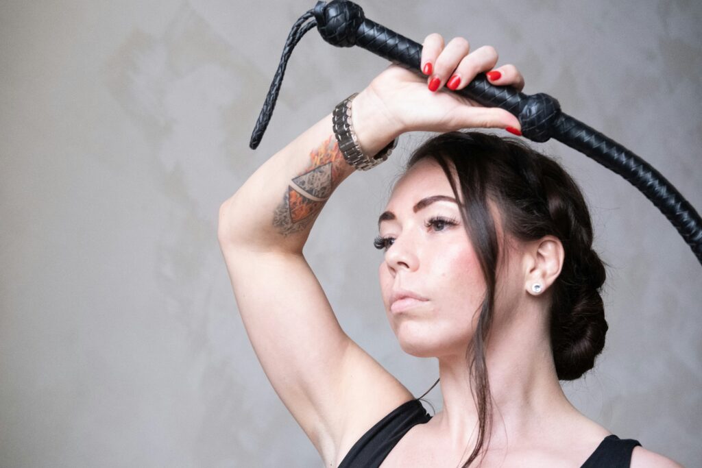 a woman with a tattoo on her arm holding a whip