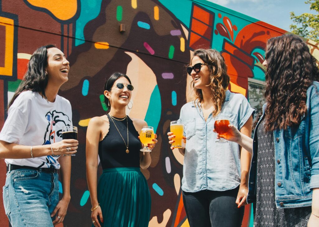 four women holding drinks while-laughing together during daytime