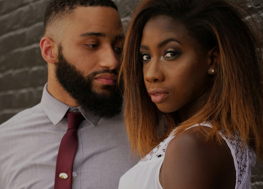 man embracing woman in front of gray wall