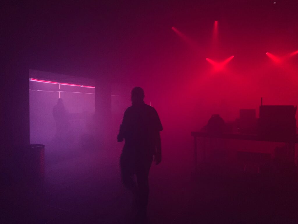 a person standing in a dark room with red and purple lights