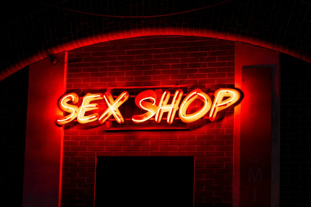 a neon sign that reads sex shop on a brick wall