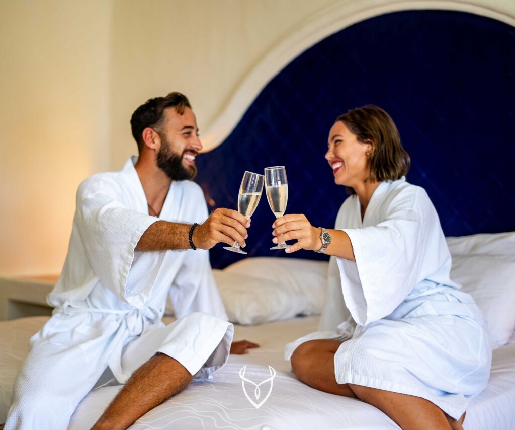 Couple with champagne on bed in hotel room