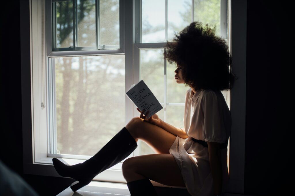 An image of a woman in window reading a book