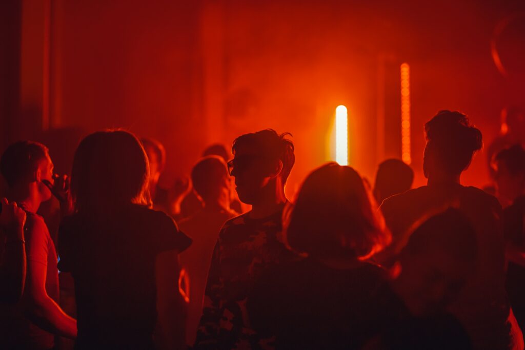 People are standing in the crowd under red light