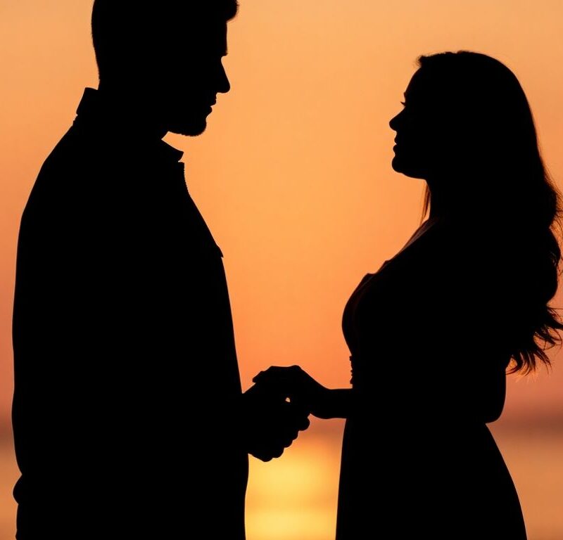 Couple holding hands in soft, warm light.