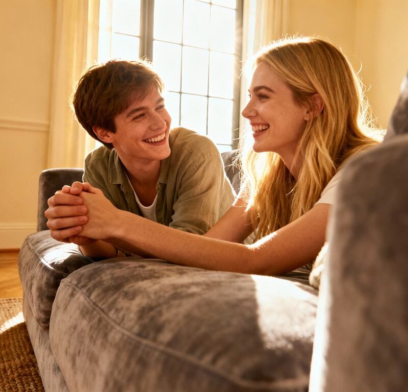 Couple holding hands in a sunlit room.