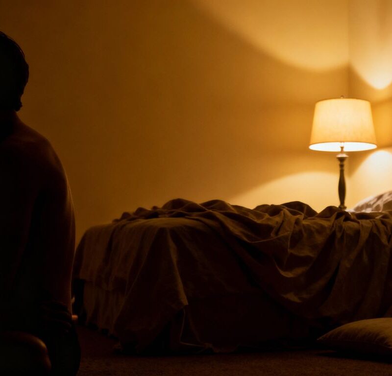 Couple in a dimly lit bedroom, suggesting discretion.