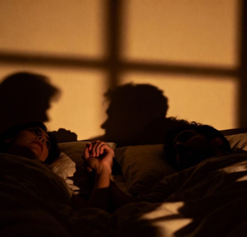 Couple in a dimly lit room, hinting at secret communication.