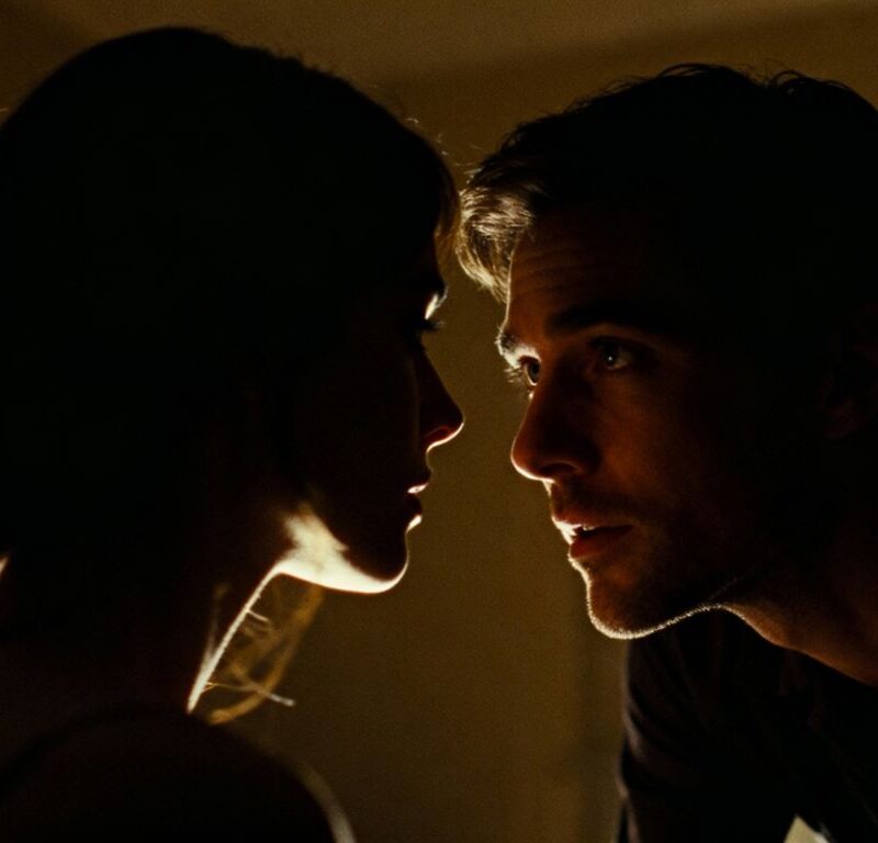 Couple in a dimly lit room, woman looking away.