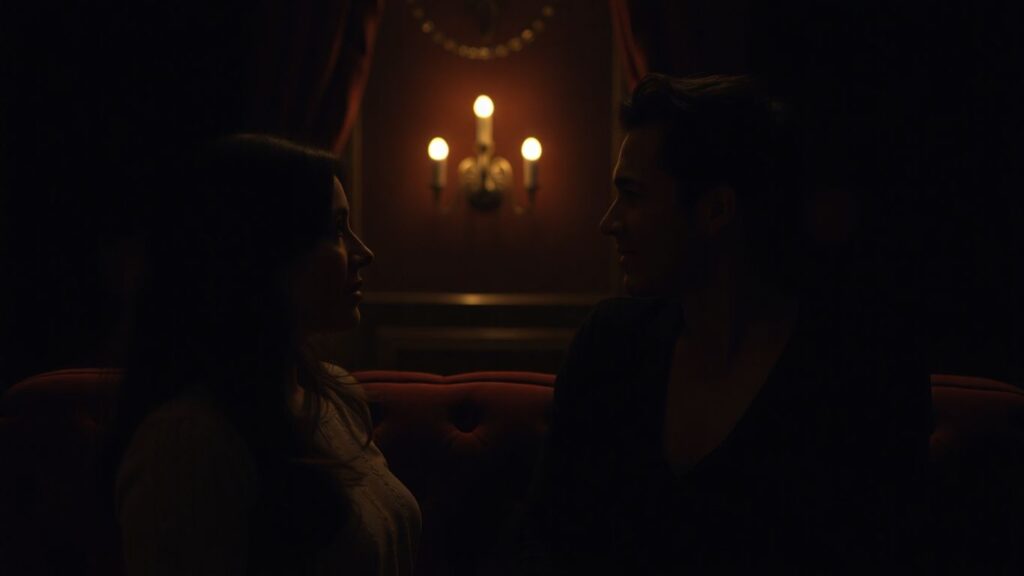 Couple sharing a secret glance in a dimly lit, intimate setting.