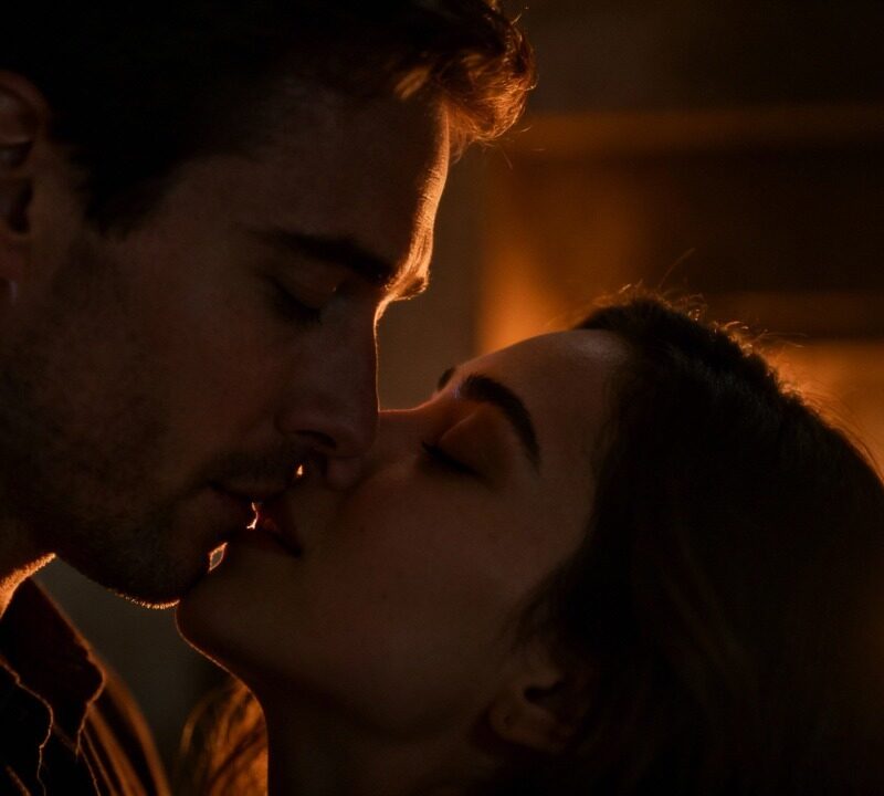 Couple embracing intimately, warm lighting.