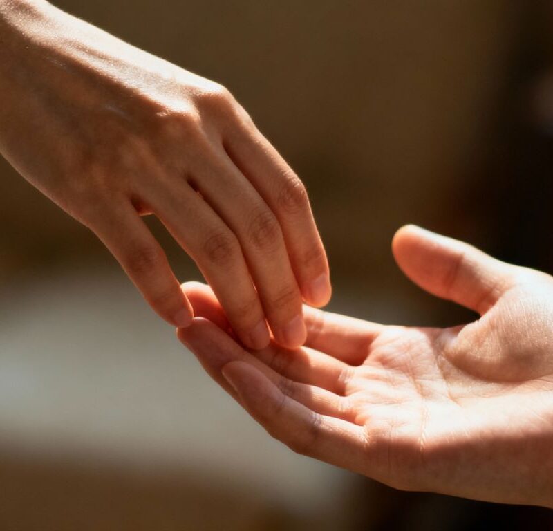 Hands gently touching in warm, intimate lighting.