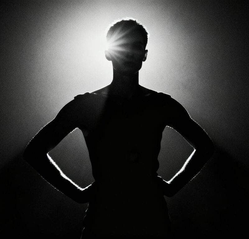 Person confidently posing under a spotlight.