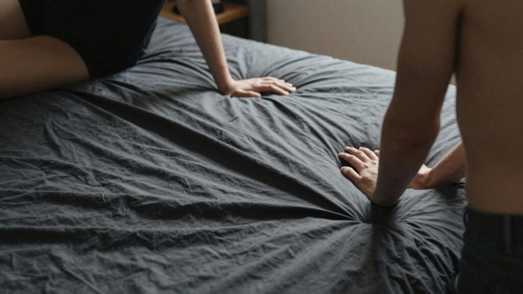 Couple in a bedroom with a black sheet.