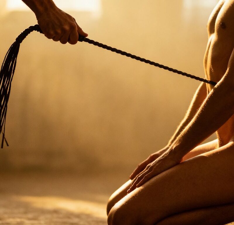 Couple in erotic flagellation scene with whip.