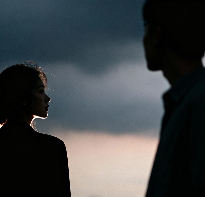 Couple looking distant against a stormy sky.