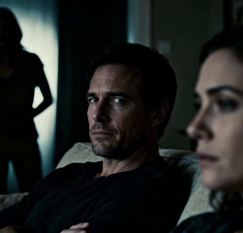 Couple looking suspicious, woman lurking in shadows.