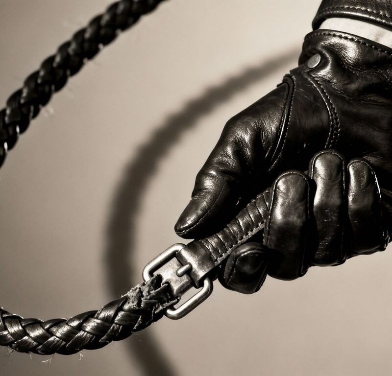 Leather whip and hand in BDSM context.