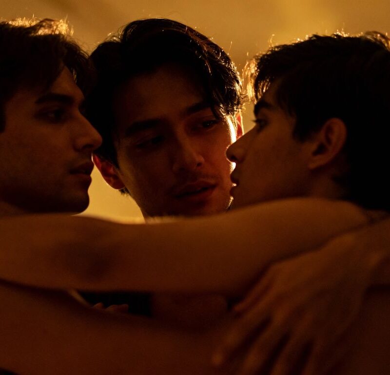 Three people in an intimate, connected pose.