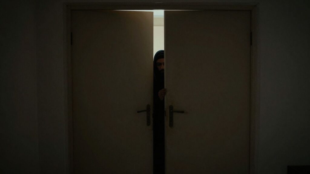 Closet door ajar, silhouette inside, soft light spilling out.