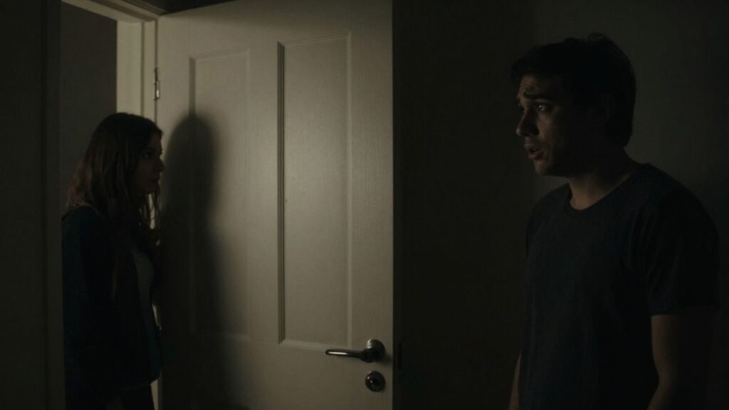 Couple in shadows, worried, closed door, intimate tension.