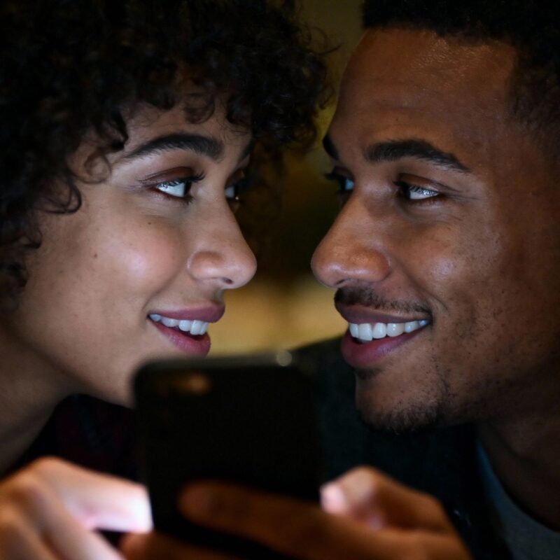 Couple intimately communicating via smartphone during online dating.
