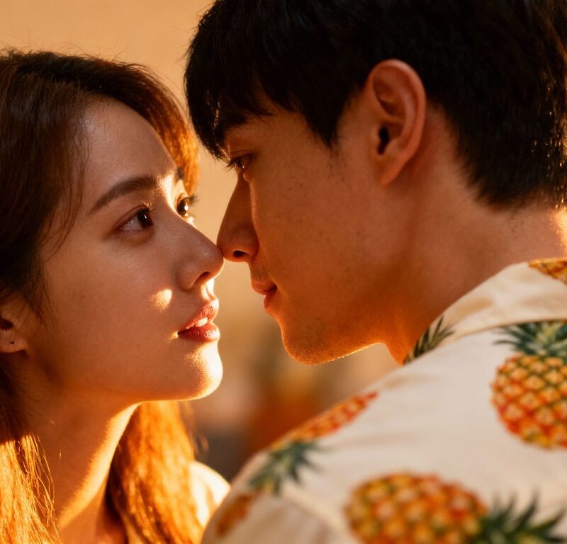 Couple sharing a secret glance, one wearing pineapple shirt.