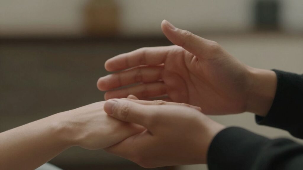 Couple's hands touching gently, conveying trust and anticipation.