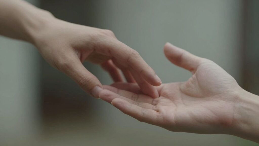 Hands gently touching in soft, intimate lighting.
