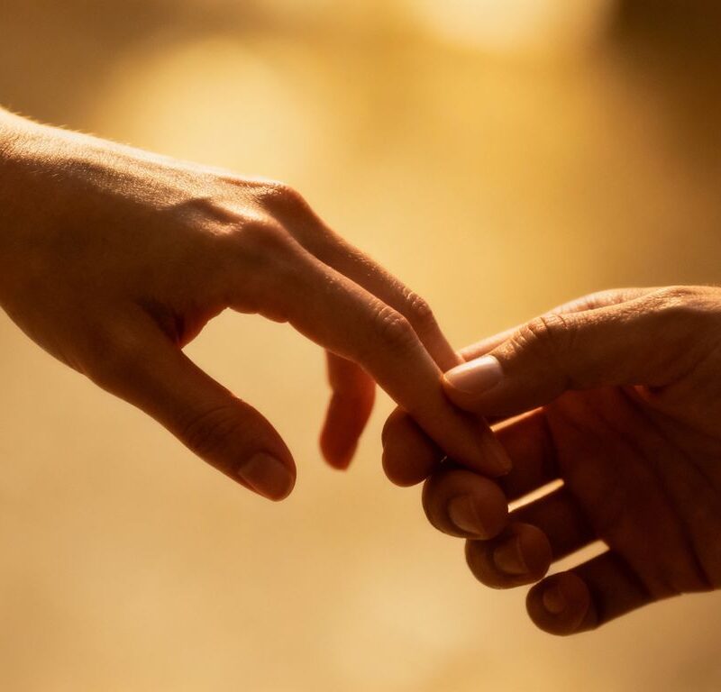 Hands touching intimately, soft lighting, blurred background.