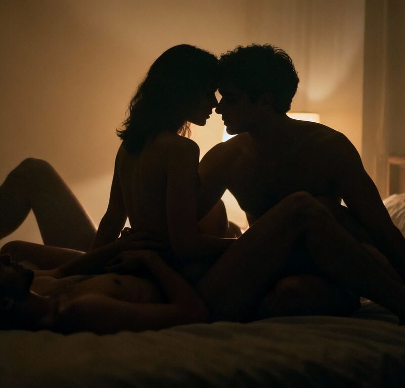 Intimate group play in a dimly lit bedroom.