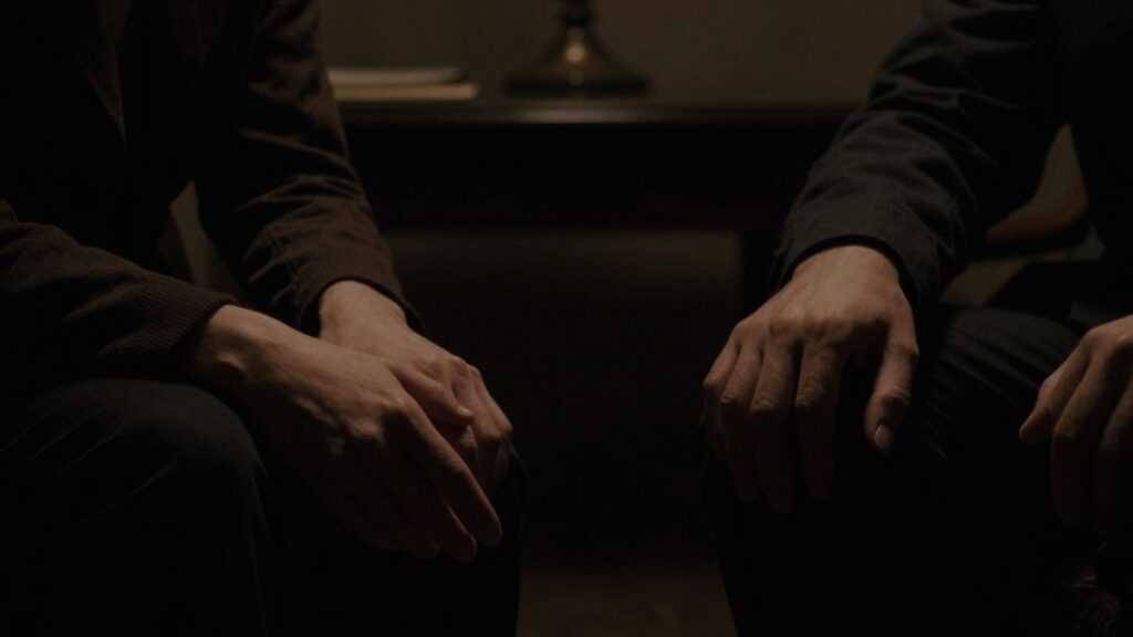 Two figures in a dimly lit, private space.