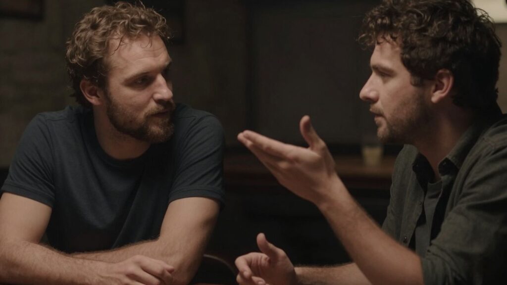 Two men in a dimly lit, intimate setting.